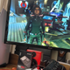a photo of the playstation 5 next to a television screen showing marvel's avengers
